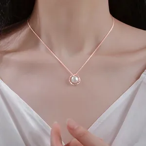 Elegante collana in oro rosa con ciondolo a perla bianca rotonda indossata da una modella