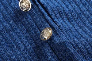 Dettaglio del tessuto in maglia a coste blu e bottoni dorati decorativi su un vestito