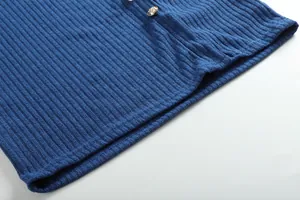 Vista macro della trama del tessuto a maglia a coste blu e del dettaglio del bottone d'oro