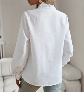 Vista trasera de blusa blanca con textura de burbujas, cuello de volantes y manga larga