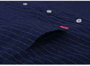 Macro view of navy blue pinstripe shirt showing pocket detail and white buttons.