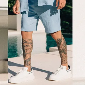 Detailed view of men's light blue textured summer shorts and white sneakers by a swimming pool