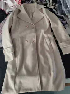 Detailed view of a light beige double-breasted wool trench coat with classic lapel design.