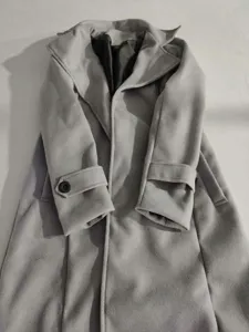 Macro view showing the soft wool fabric and lapel design of the grey long trench coat.