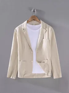 Blazer décontracté pour homme en coton et lin beige suspendu à un cintre sur un mur gris.