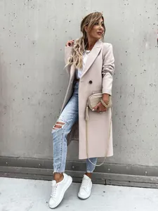 Full length view of a woman wearing a chic beige long woolen coat and ripped blue jeans