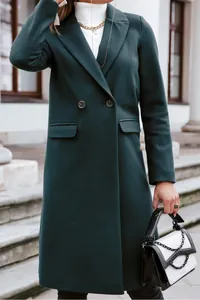 Detailed view of an elegant dark green long wool coat with lapel collar and side pockets for women