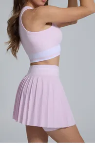 Side profile view of a pink pleated tennis skirt and matching sports bra on a model