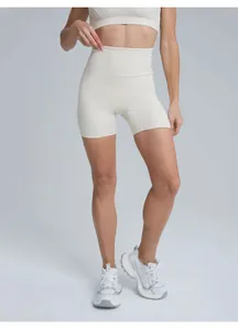 A detailed front view of women's high-waisted beige athletic yoga shorts in studio