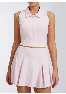 Primer plano de un conjunto de yoga rosa claro con top de cremallera y falda plisada.