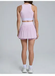 Back view of athletic woman wearing a pink pleated tennis skirt and crop top sports set