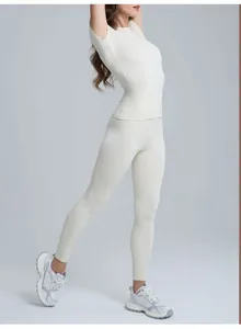 Vista laterale di una donna che indossa un set top yoga a maniche corte crema e leggings