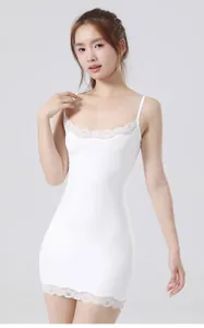 Full view of a white camisole dress showing the slim fit and lace detailing on a model