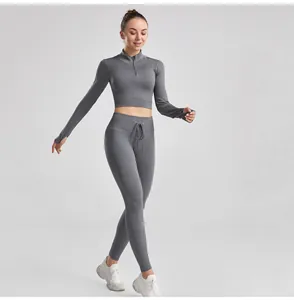 Model wearing a grey ribbed two-piece yoga set with drawstring leggings and zipper top