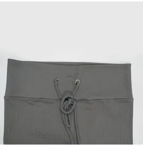 Primo piano dettagliato della fascia in vita e del cordoncino dei pantaloni yoga grigi a costine
