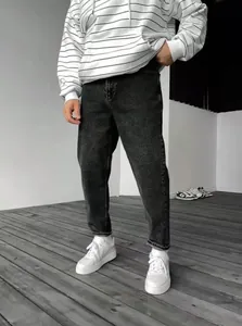 Vue détaillée d'un jean en denim gris foncé pour homme avec des baskets blanches