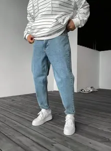 Jean bleu clair coupe slim pour homme avec baskets blanches et sweat à capuche.