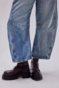 Dettaglio di jeans in denim lavaggio chiaro vestibilità comoda con stivaletti marrone scuro spessi