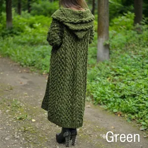Achteraanzicht van een lange groene gebreide kabelvest met capuchon in een bos