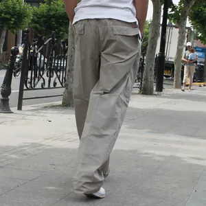 Vista trasera de pantalones cargo caqui holgados para hombre en entorno urbano.