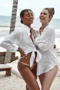 Dos mujeres vestidas con camisas de playa de lino blanco en una soleada playa tropical