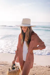 Modelo con una camisa playera naranja óxido de tela arrugada en una playa soleada