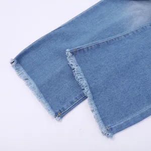 Primo piano del bordo a taglio vivo sfrangiato e delle cuciture su un jeans blu lavato