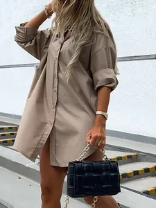 Fashionable model wearing khaki oversized cotton shirt dress styled with black quilted bag