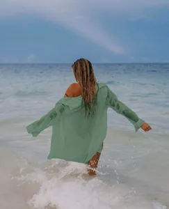 Vista trasera de una camisa playera verde de tela rugosa entre las olas del mar