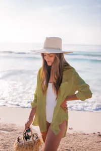 Camisa playera transparente verde oliva de tela rugosa llevada por una modelo en la playa