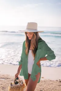 Modelo con camisa de playa verde sobre bikini blanco en una playa muy soleada