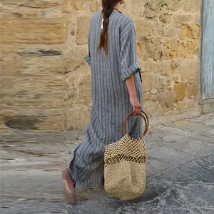 Vue arrière d'une élégante robe longue en lin rayé avec un sac en paille rustique