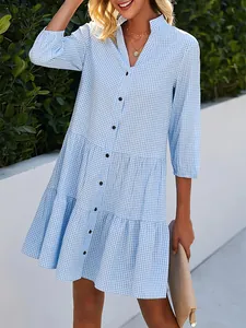 Détail d'une robe chemise à carreaux bleu clair à volants avec col officier et boutons