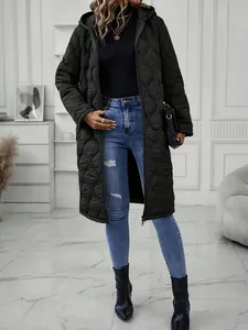 Close-up of long black quilted hooded jacket worn with ripped jeans in a modern setting