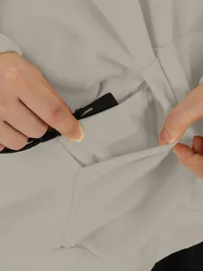 Detalle del diseño de bolsillo oculto y salida de cables en sudadera beige de mujer