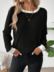 Primer plano del top de manga larga de canalé negro con cuello y puños blancos en contraste.