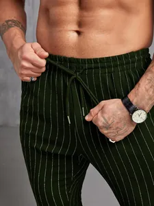 Gros plan d'un pantalon rayé vert foncé pour homme avec cordon de serrage réglable.