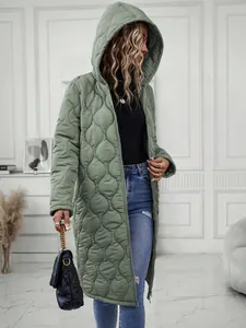 Woman in a long sage green quilted hooded jacket, showing modern casual fashion style.