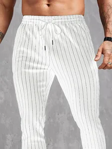 Gros plan sur un pantalon blanc pour homme à rayures noires verticales et taille à cordon