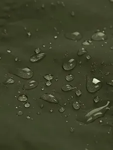 Macro shot of waterproof green fabric showing water beads on an outdoor hiking jacket