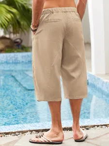 Detailed back view of men's casual khaki linen beach shorts worn by a sunny swimming pool