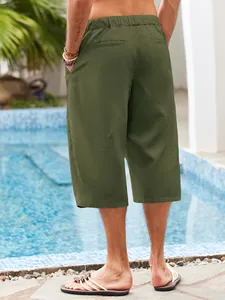 Close-up back view of men's olive green linen cotton casual beach shorts by a pool