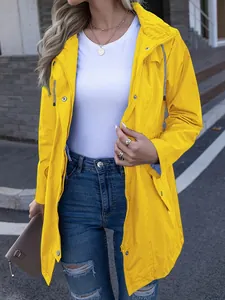 Détail d'un coupe-vent imperméable ajusté jaune vif pour femme dans un cadre extérieur.