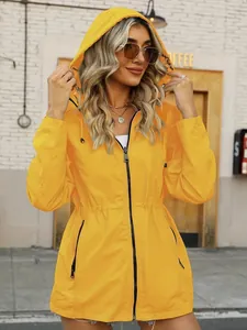 Model wearing a bright yellow hooded waterproof windbreaker in a stylish outdoor setting