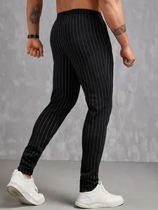 Vue arrière d'un pantalon décontracté pour homme noir à fines rayures et baskets blanches