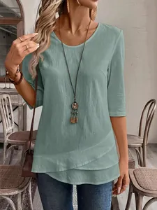 Detail view of a mint green three-quarter sleeve top with asymmetric layered hem