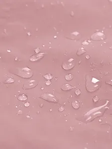 Detailed macro shot of water droplets on pink waterproof outdoor hiking jacket fabric