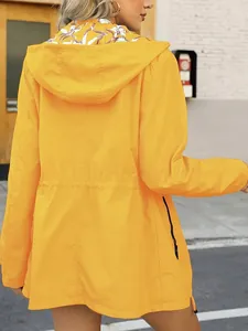 Back view of a women's bright yellow waterproof windbreaker featuring floral hood lining