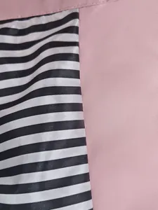 Close-up detail of a pink waterproof outdoor jacket featuring a black and white striped lining