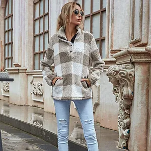 Outdoor lifestyle shot of a woman wearing a cozy plaid fleece pullover in neutral tones